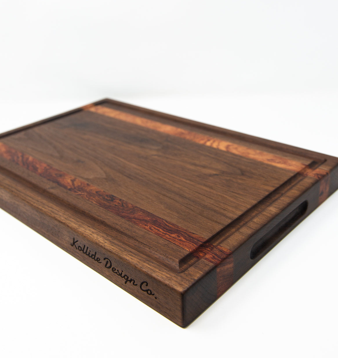 Extra large wood cutting board, made of dark walnut and two strips of dark reddish brown Bubinga, with a juice groove and side handles.