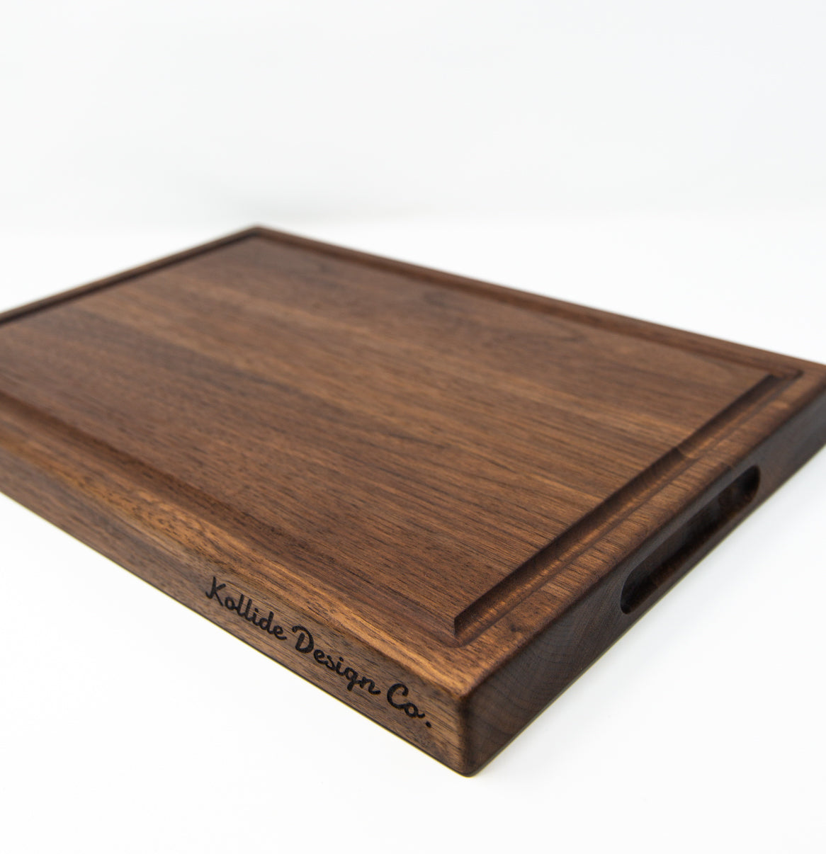 Medium size wood cutting board, made of dark walnut, with a juice groove and side handles.