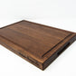 Extra large wood cutting board, made of dark Walnut, with a juice groove and side handles.