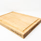 Extra large wood cutting board, made of light blonde Maple, with a juice groove and side handles.