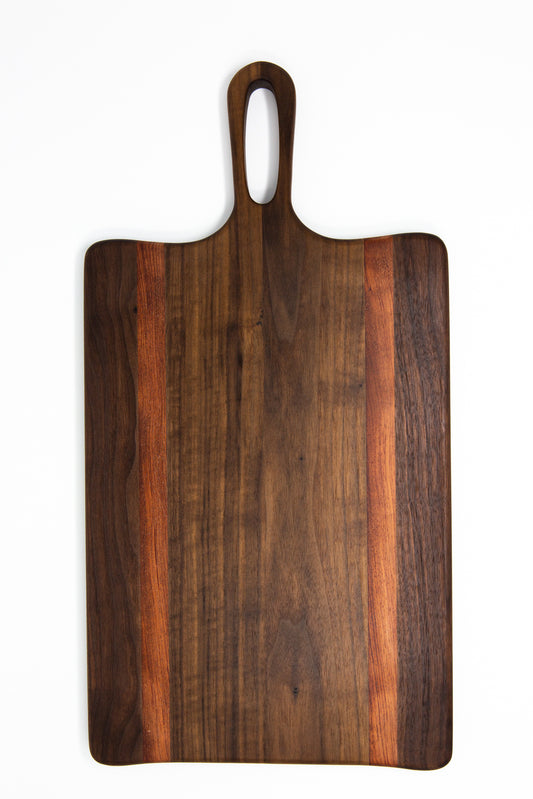 Medium size wood charcuterie board, made of a dark Walnut and two strips of dark reddish-brown Bubinga, with unique looped handle and exaggerated curves.