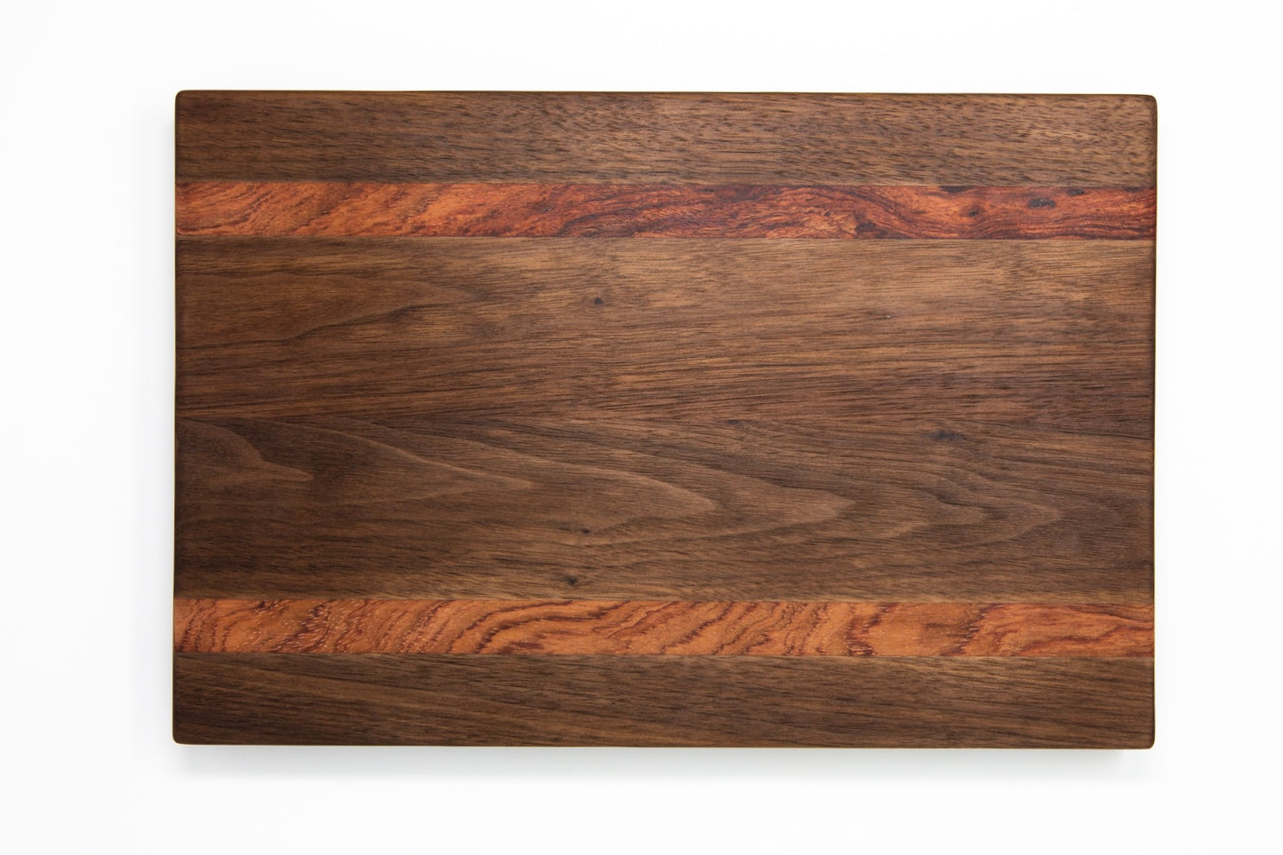 Extra large wood cutting board, made of dark walnut and two strips of dark reddish brown Bubinga, with side handles.