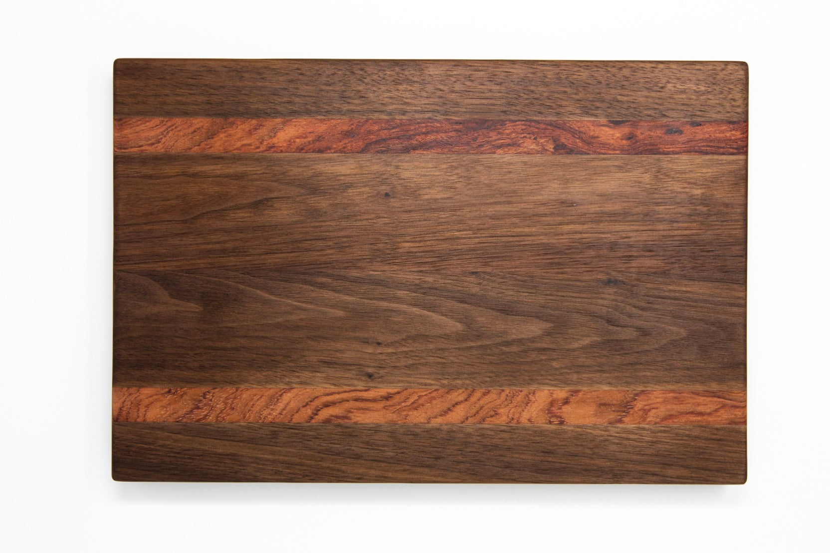 Extra large wood cutting board, made of dark walnut and two strips of dark reddish brown Bubinga, with side handles.