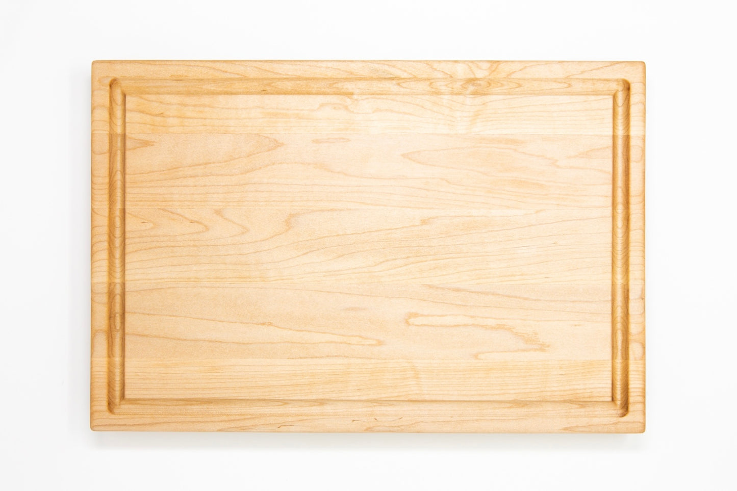 Medium size wood cutting board, made of light blonde Maple, with a juice groove and side handles.